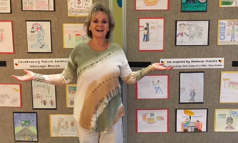 Luella Wagner teaching in a classroom with student artwork behind her